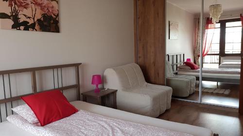 a bedroom with a bed and a chair and a mirror at Villa Sole in Pruszcz Gdański