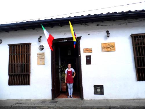a woman standing in the doorway of a white building with flags at Giron Chill Out Hotel Boutique in Girón