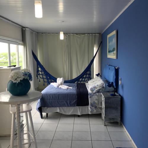 a bedroom with a bed and a blue wall at Hotel Rainha in Itapoa