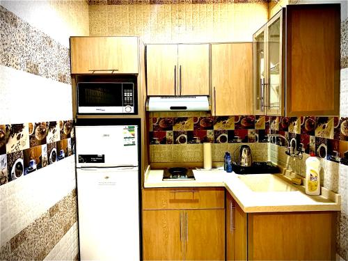 a kitchen with wooden cabinets and a white refrigerator at شقق حدائق الزيتون للوحدات السكنية -اقتصادية in Hail
