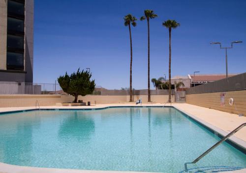 a large swimming pool in a building with palm trees at Holiday Inn Victorville by IHG in Victorville