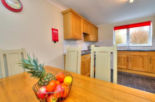 a bowl of fruit on a wooden table in a kitchen at Hampson House Stevenage by PAY AS U STAY in Stevenage