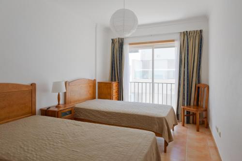 a hotel room with two beds and a window at Monte Gordo Beach Flat with Balcony in Monte Gordo