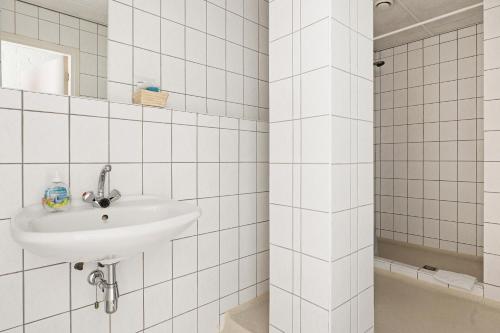 ein weiß gefliestes Bad mit einem Waschbecken und einer Dusche in der Unterkunft Hotel de Waalehof in Jipsinghuizen