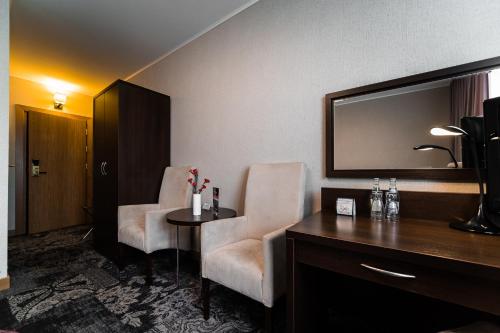 a hotel room with two chairs and a desk and a mirror at Hotel Coloseum in Jarosław