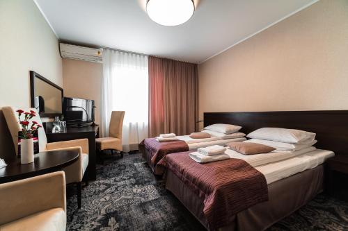 a hotel room with two beds and a desk at Hotel Coloseum in Jarosław