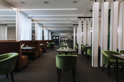 a dining room with tables and green chairs at Panorama Hotel in Izhevsk