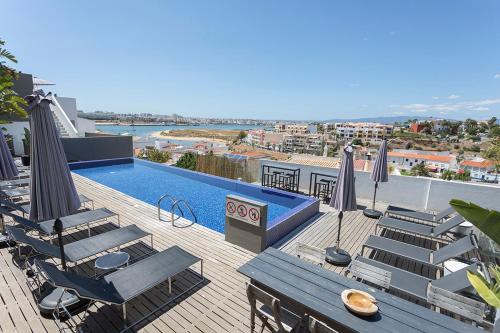 a swimming pool with chairs and umbrellas on a deck at One2Seven in Ferragudo