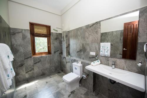 a bathroom with a sink and a toilet and a mirror at Mount Rich Rumassala By JMS Group in Unawatuna