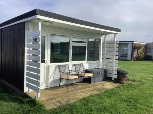 a small white shed with a chair in a yard at 245 Sundowner in Hemsby
