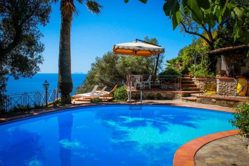 uma piscina com um guarda-sol e o oceano em Villa l'Infinito em San Felice Circeo
