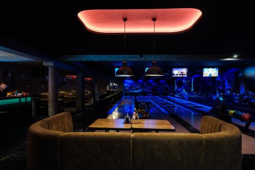 a bowling alley with a couch and tables in a bar at Hotel Coloseum in Jarosław