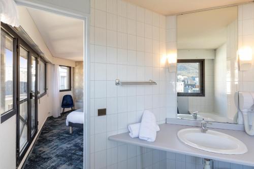 La salle de bains est pourvue d'un lavabo et d'un miroir. dans l'établissement Hôtel National, à Lourdes