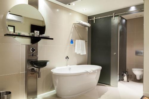 a bathroom with a toilet, tub, sink and shower at Colosseum Luxury Hotel in Cape Town