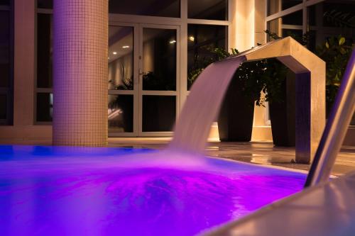 a purple water fountain in front of a building at Hotel Nowy Dwór Elizy blisko Sky Bridge in Długopole-Zdrój