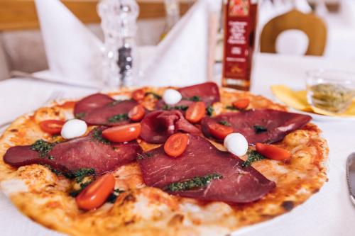 a pizza with ham and tomatoes on a table at Zur Mühle Wohlfühloase in Trodena