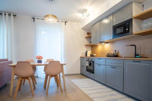 une cuisine avec des armoires bleues, une table et des chaises dans l'établissement Dream Stay - Brand New Apartment with Balcony & Free Parking, à Tallinn