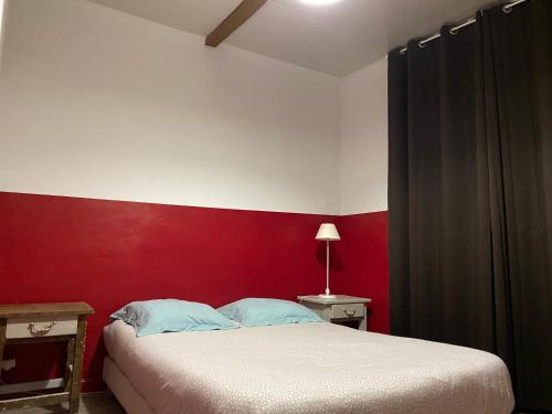 Un dormitorio con una pared roja y una cama en L'Éphémère Canebière - Gambetta, en Marsella