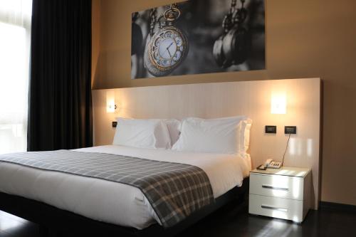 a bed in a hotel room with a clock on the wall at Hotel Garibaldi in Vercelli