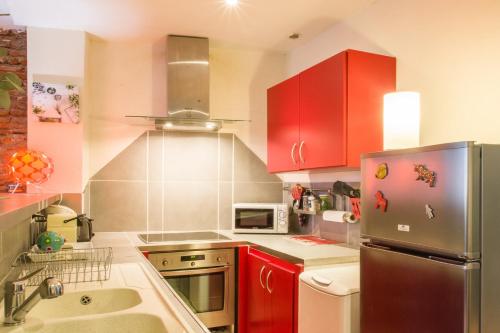 uma cozinha com armários vermelhos e um frigorífico de aço inoxidável em Rosa Bonheur by Cocoonr em Toulouse