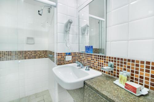 a white bathroom with a sink and a shower at Savoy Othon in Rio de Janeiro