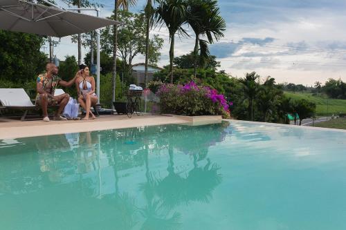 two women are sitting next to a swimming pool at Visus Hotel Boutique & Spa in Pereira