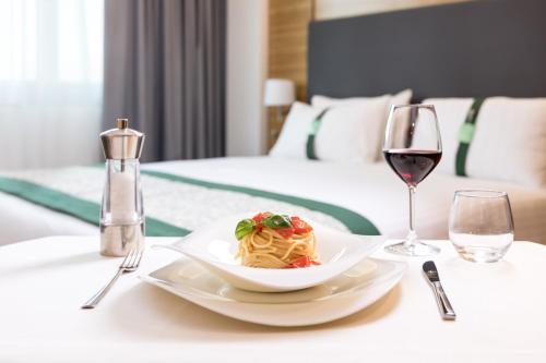 a table with a plate of pasta and a glass of wine at Holiday Inn Naples by IHG in Naples