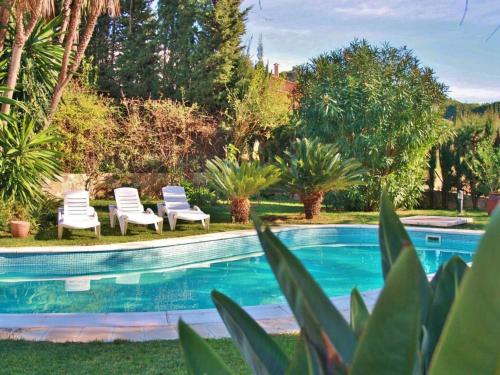 una piscina con 2 sillas y árboles en Belvilla by OYO Casa Jaume, en Sant Pol de Mar