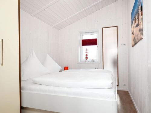 ein weißes Schlafzimmer mit einem weißen Bett und einem Fenster in der Unterkunft Dänische Ferienhäuser am Salzhaff Haus Vogelparadies in Insel Poel