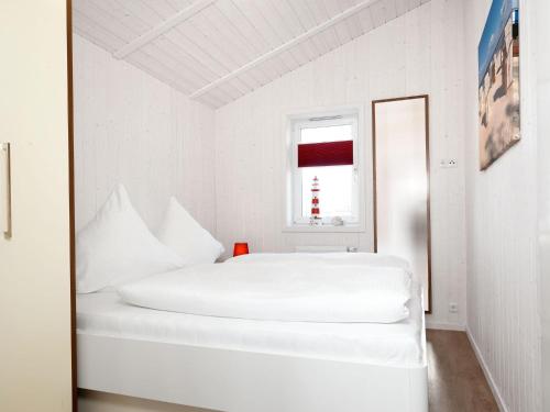 une chambre blanche avec un lit blanc et une fenêtre dans l'établissement Dänische Ferienhäuser am Salzhaff Haus Vogelparadies, à Poel
