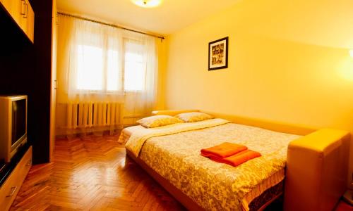 モスクワにあるKvartiraSvobodna - Apartments Rublevskoe shosse 5のベッドルーム1室(オレンジのシーツが入ったベッド1台、テレビ付)