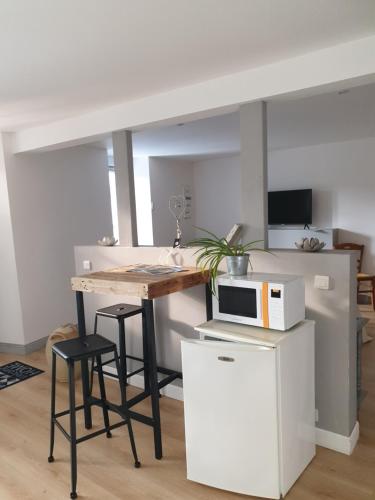 - une cuisine avec une table, un four micro-ondes et des tabourets dans l'établissement La jolie chambre, à Javrezac