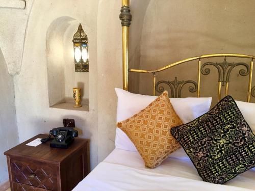 a bed with pillows and a camera on a table at Djorff Palace in Luxor
