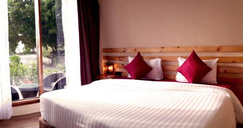 a bedroom with a bed with red pillows and a window at Endheri Sunset Dhangethi in Dhangethi