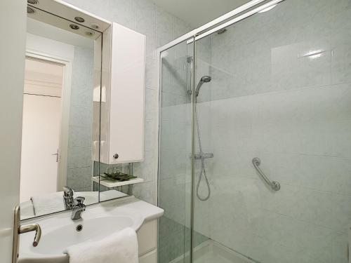 uma casa de banho com um lavatório e um chuveiro com uma porta de vidro em Horizons "Vue Mer" em Royan