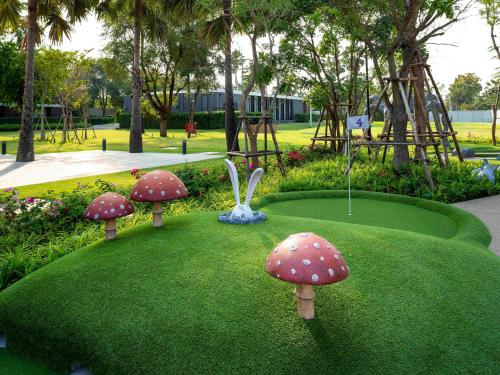 a park with mushrooms on the grass with a playground at SO/ Sofitel Hua Hin in Cha Am