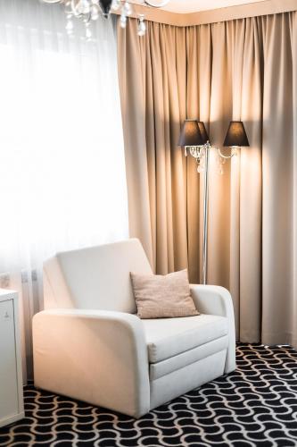 a living room with a white chair and a lamp at Hotel Coloseum in Jarosław