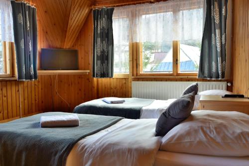 una camera con due letti, una TV e finestre di Apartament Sosna a Zakopane