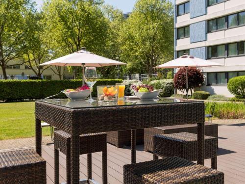 a table with two chairs and an umbrella at Mercure Hotel Mannheim am Friedensplatz in Mannheim