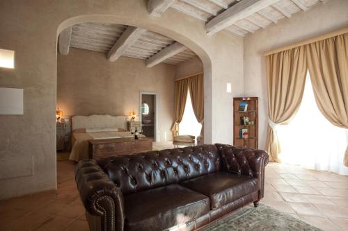 sala de estar con sofá de cuero y cama en Casanova di Neri Relais en Montalcino