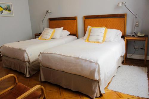 two beds in a hotel room with yellow pillows at Zero Hotel in Valparaíso