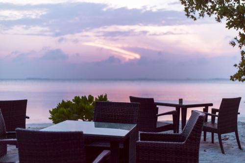 a table and chairs with a view of the ocean at Endheri Sunset Dhangethi in Dhangethi