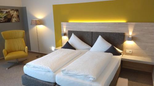 ein Schlafzimmer mit einem großen Bett und einem gelben Stuhl in der Unterkunft BurgStadt-Hotel in Kastellaun