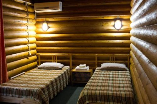 ガリャーチ・クリュチにあるПоместье Холодный Ручейのログキャビン内のベッド2台が備わる部屋です。