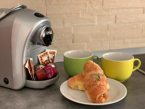 a toaster and a plate of pastries next to two cups at Maison Belle Vue in Chioggia