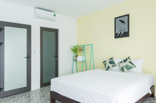 a white bedroom with a white bed and a mirror at Sunny Riverside Homestay in Hoi An