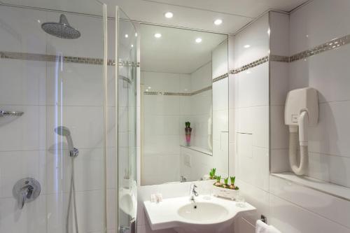 une salle de bain blanche avec un lavabo et une douche dans l'établissement Virgina, à Paris