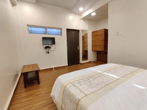 KudālにあるHotel Surya Grandeのベッドルーム1室(ベッド1台、壁掛けテレビ付)