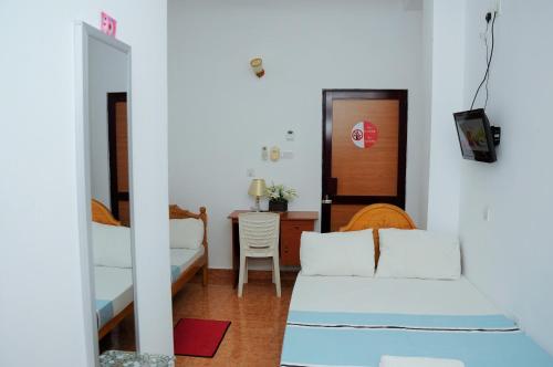 a room with a bed and a table and a mirror at Hotel Juli Reception in Mannar