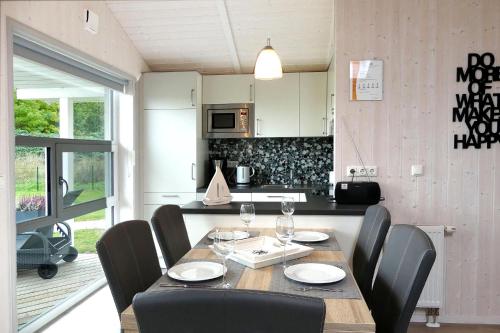 a dining room table with chairs and a kitchen at Dänische Ferienhäuser am Salzhaff Haus Poseidon in Insel Poel